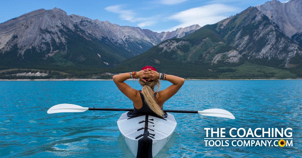 Summer Life Coaching Exercises shown by woman kayaker on lake with mountains